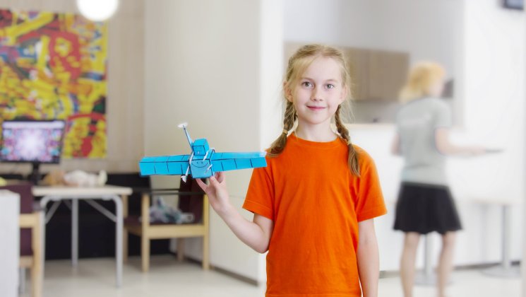 Pildil on näha tüdrukut, kes hoiab käes paberist meisterdatud satelliiti. Autor Viljo Allik